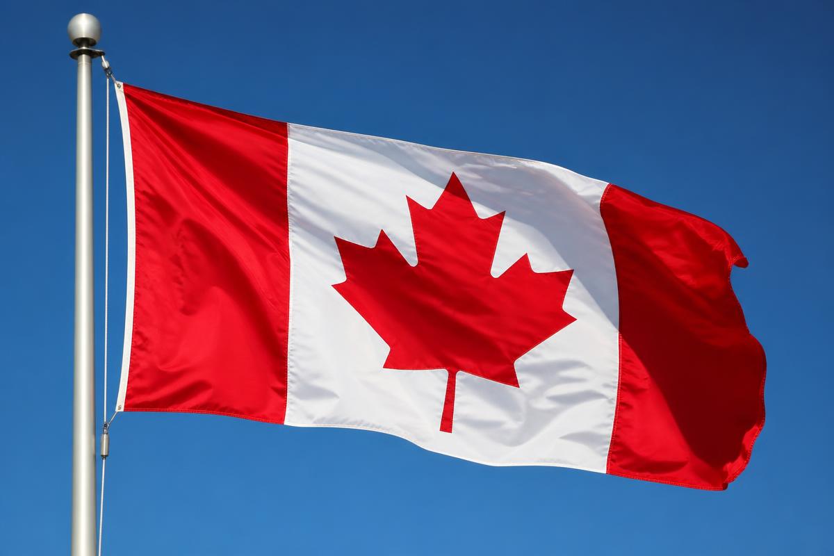 The Canadian flag flying against a clear blue sky